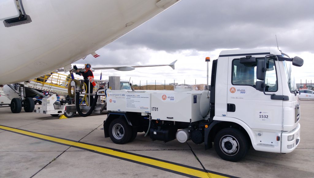 Fuel truck servicing an airplane on the tarmac, with a technician operating equipment near the aircraft.