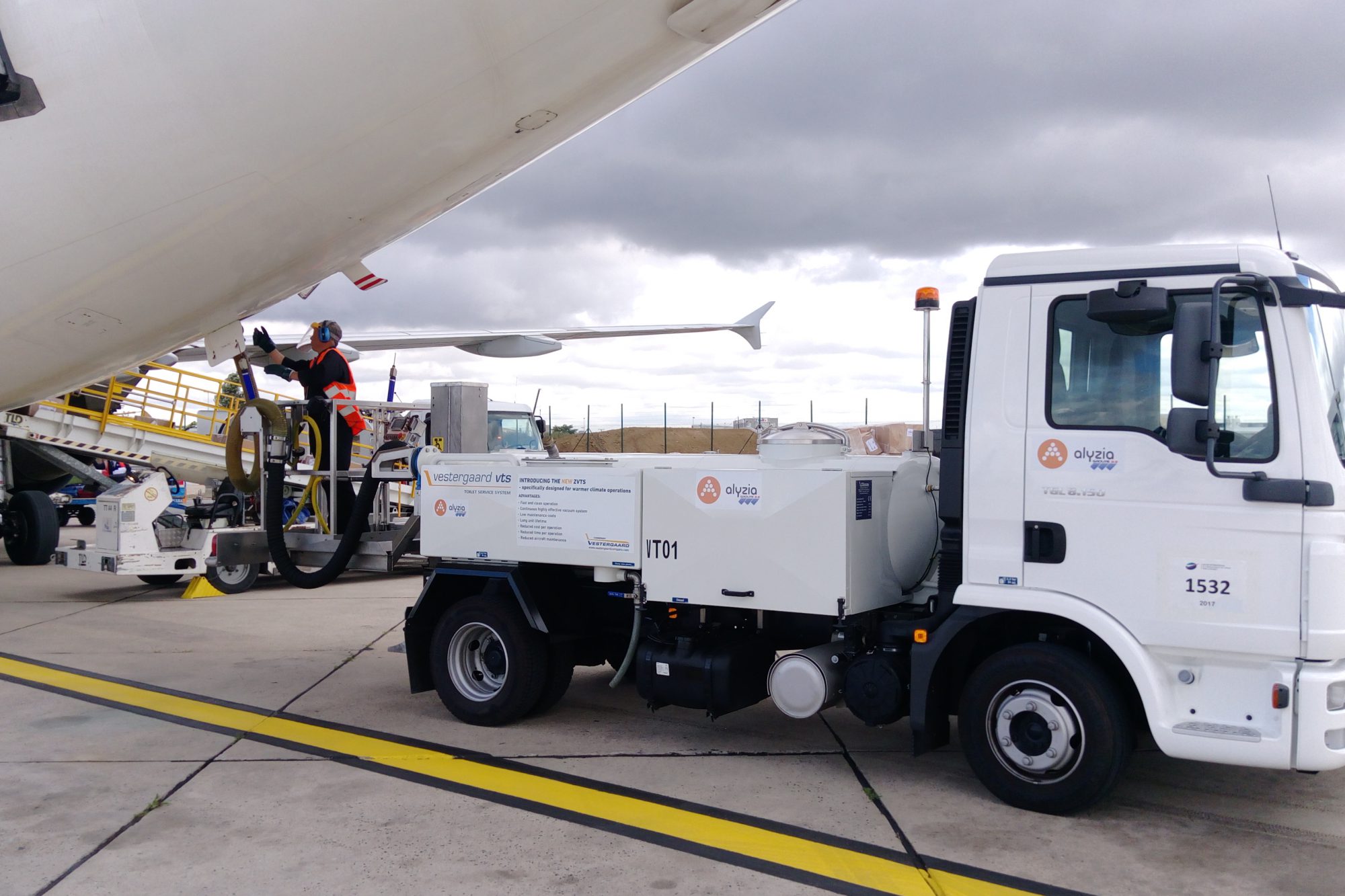 Fuel truck servicing an airplane on the tarmac, with a technician operating equipment near the aircraft.