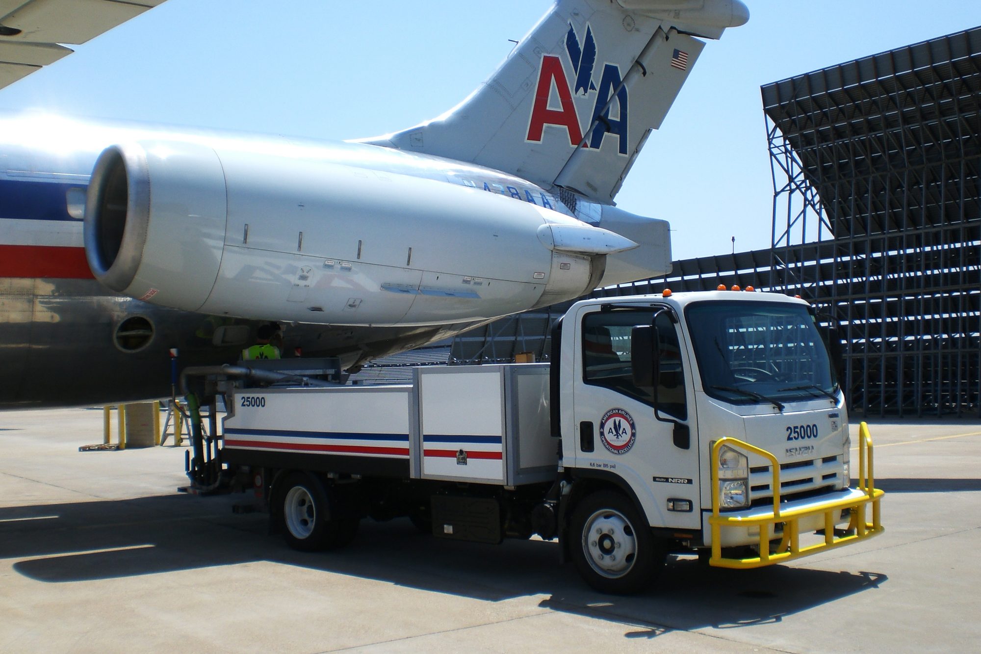 American Airlines aircraft with a ground service vehicle positioned underneath, ready for maintenance or refueling.