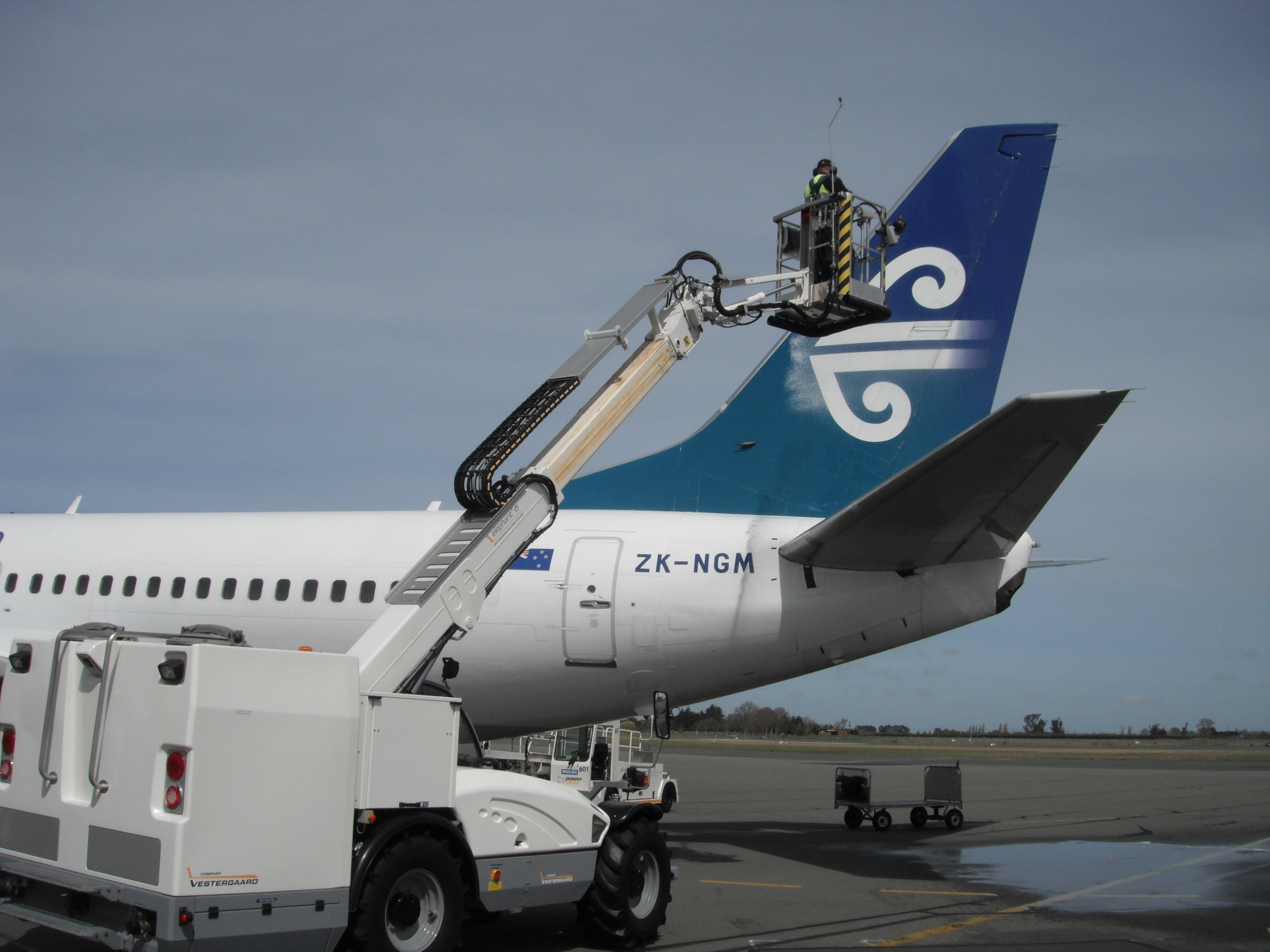Technician working on the tail of an Air New Zealand aircraft, registration ZK-NGM, using a lift.