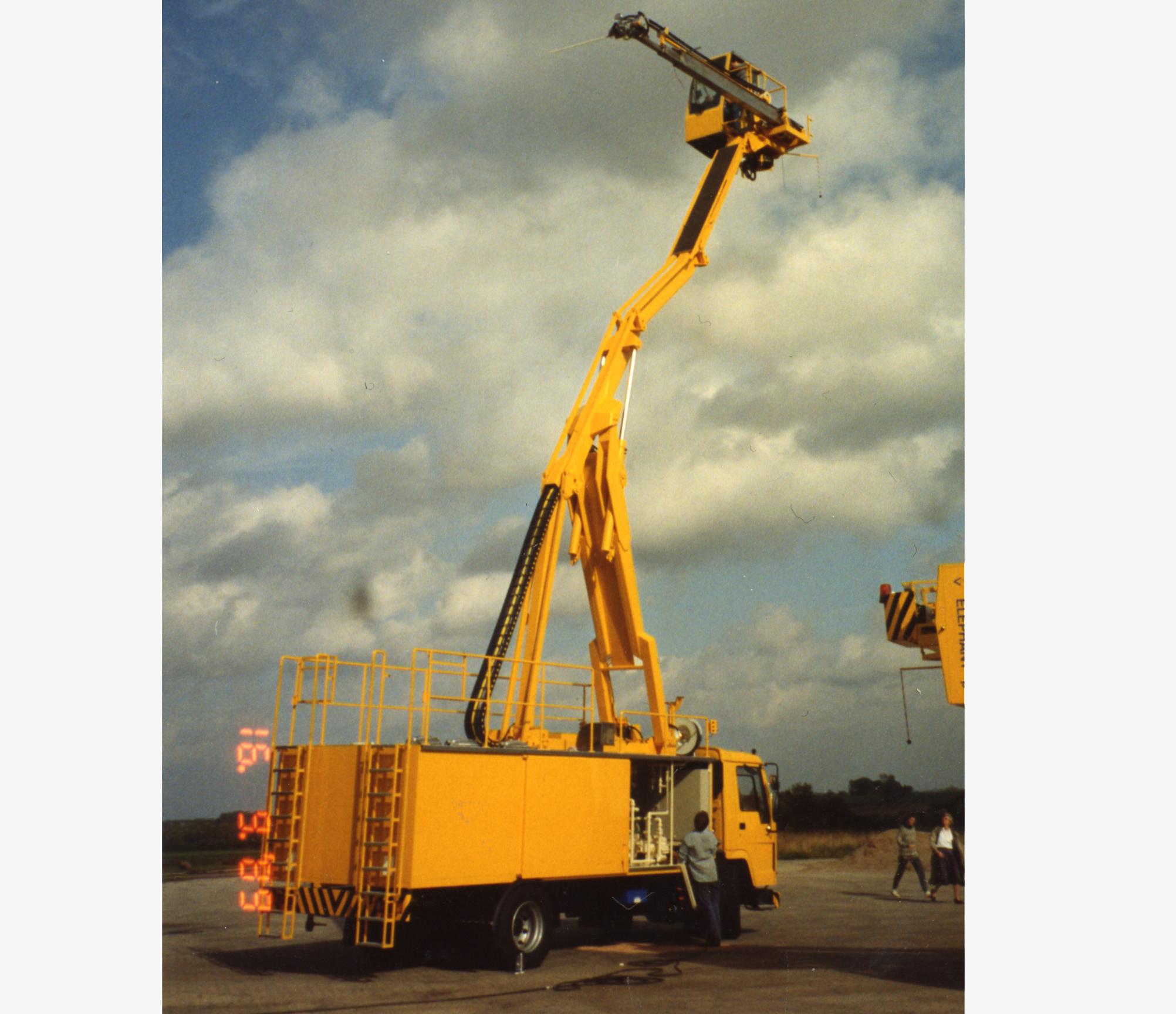 Yellow aerial work platform truck with extended boom, used for reaching high places.