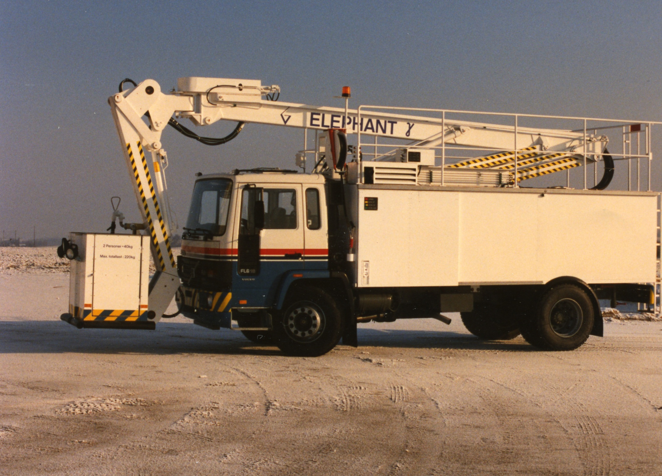 Elephant truck with a crane arm extended, parked on a snowy surface, designed for lifting and maintenance tasks.