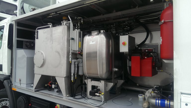 Industrial equipment with a silver tank, a gray container, and red components, housed in a truck compartment.