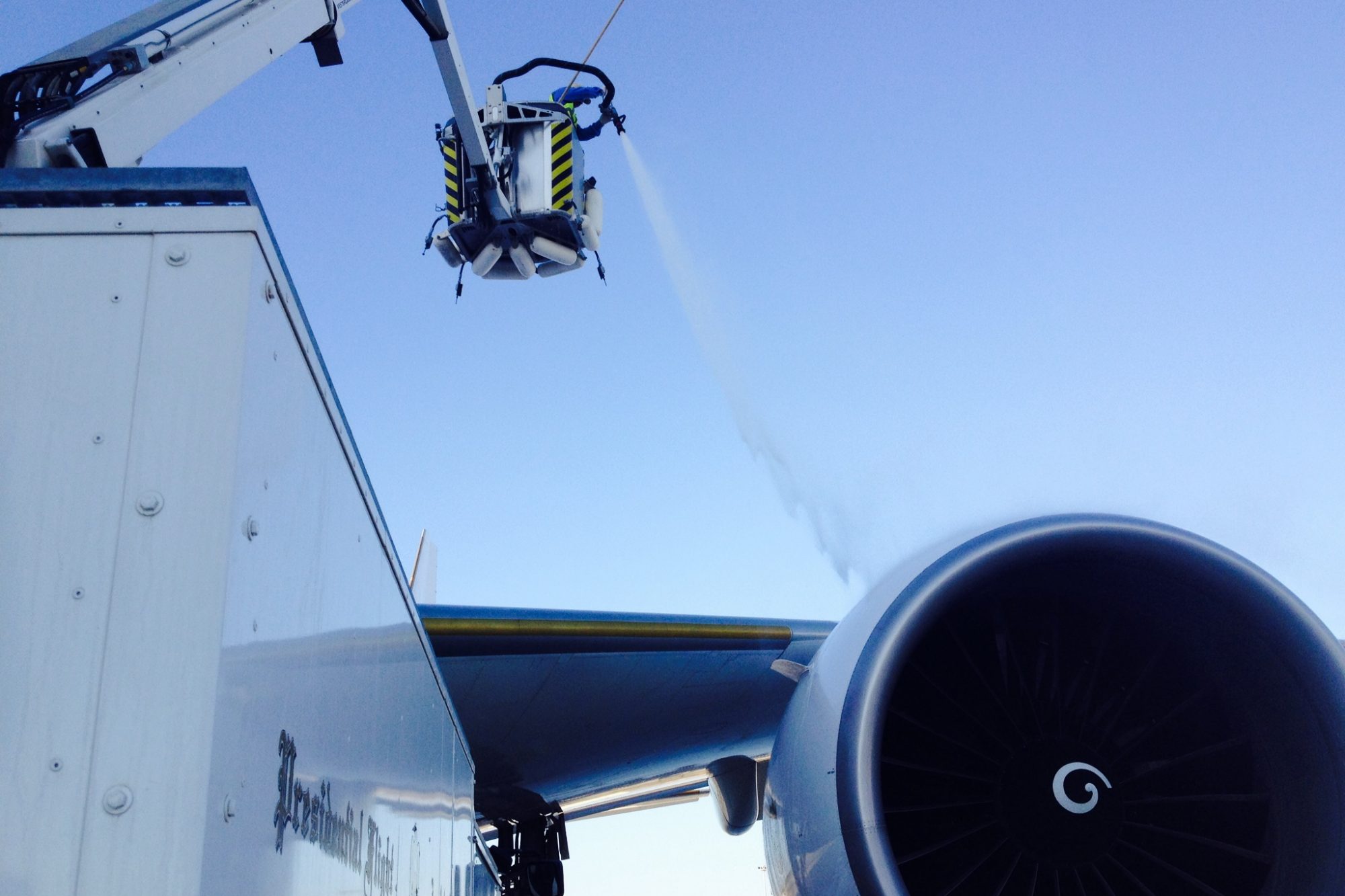 A de-icing vehicle sprays liquid onto an airplane engine, ensuring safe operation in cold weather conditions.