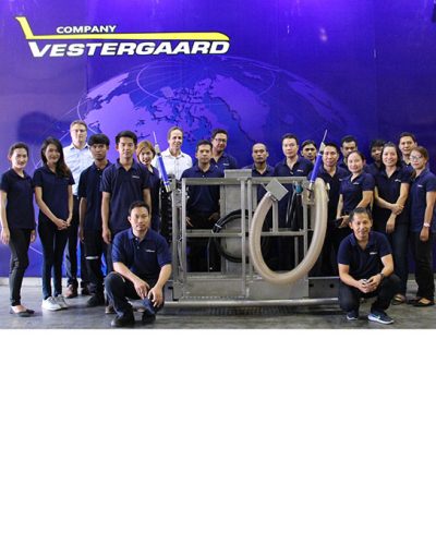 Vestergaard company team poses together with equipment in front of a blue backdrop featuring a world map.