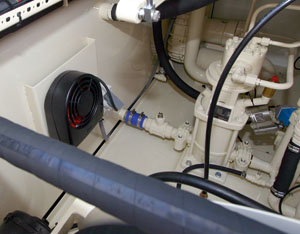 Interior view of machinery with pipes, hoses, and a fan, showing a complex arrangement of components.